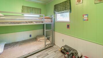A bunk bed room with a window, a toy car, and a wall with a seashell decoration.