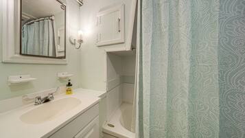 A bathroom with a white sink, a mirror, a towel rack, and a shower curtain.