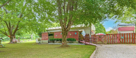 Una propiedad residencial con patio cercado, terraza de madera y una casa de fachada roja.