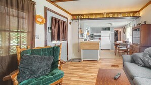 Un salon avec un plancher en bois, un fauteuil vert, un canapé gris et une table basse en bois.