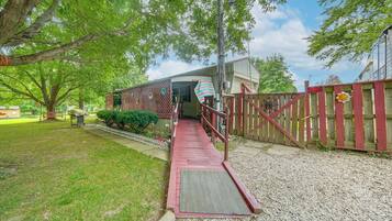A property with a covered porch, a fenced yard, and a gravel pathway leading to a building.