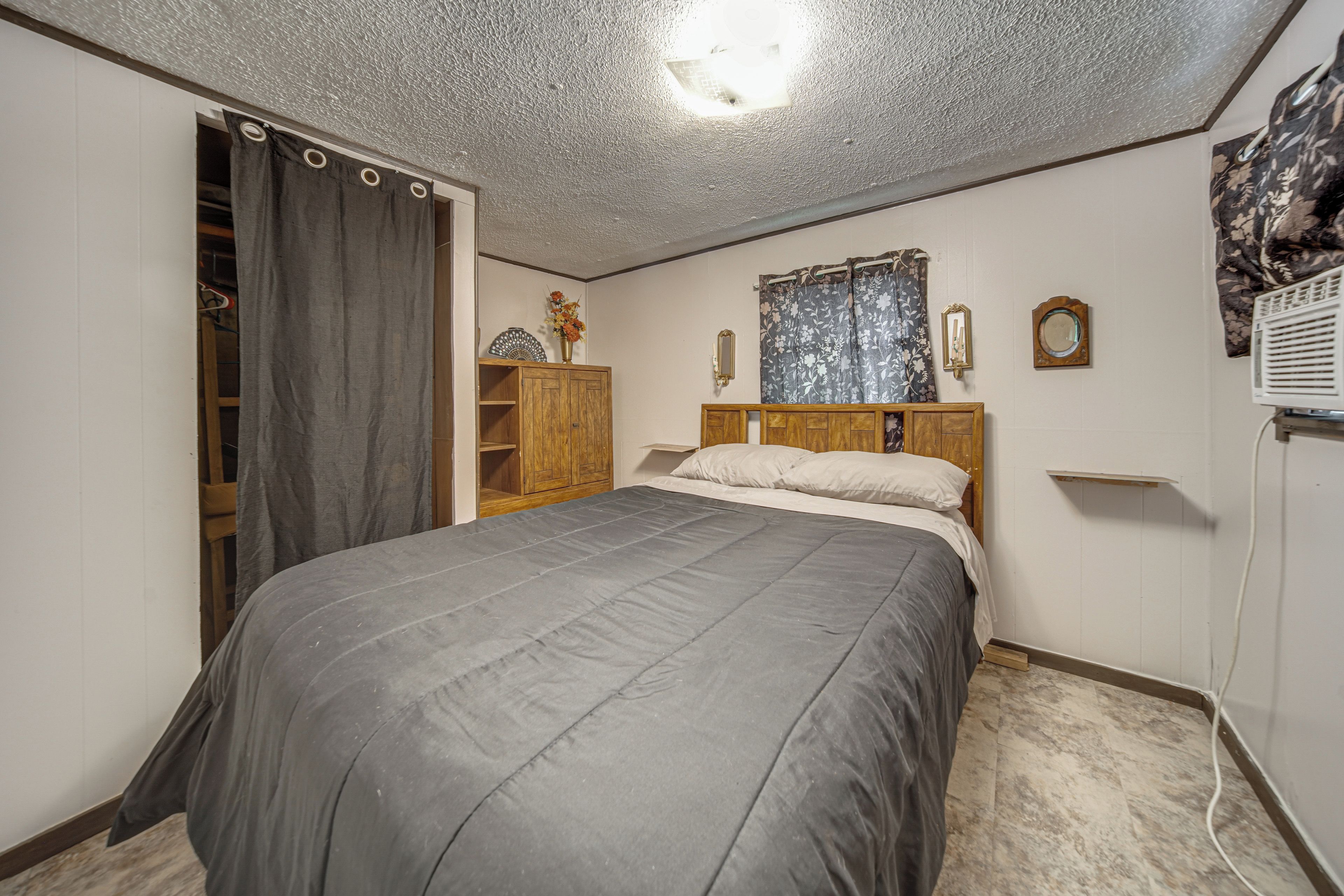 Une chambre à coucher avec un lit, une armoire, un miroir et un luminaire au plafond.
