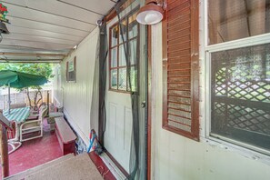 A covered porch with a table and chairs, a door, and a window with blinds. - Andover Home Near State Park w/ Patio & Yard! (Andover)