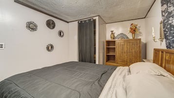 A bedroom with a bed, a wooden wardrobe, and a mirror on the wall.