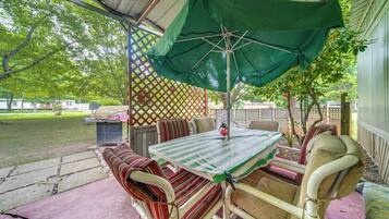An outdoor patio with a table and chairs, a green umbrella, and a lattice fence.