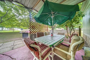 An outdoor patio with a table and chairs, a green umbrella, and a lattice fence. - Andover Home Near State Park w/ Patio & Yard! (Andover)