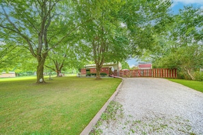 A gravel driveway leading to a house with a red fence and a grassy yard. - Andover Home Near State Park w/ Patio & Yard! (Andover)