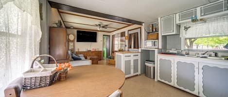 A compact kitchen with a dining area, a ceiling fan, and a television mounted on the wall.