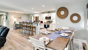 A modern kitchen with white cabinets, stainless steel appliances, and a dining area with a wooden table set for four.