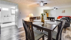 A dining area with a wooden table, chairs, and a ceiling fan. A kitchen is visible in the background. - Pet-friendly Zanesville Haven w/ Game Room! (Zanesville)