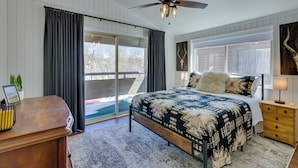A bedroom with a large bed, a ceiling fan, a desk with a lamp, and a view of the outdoors. - Cozy La Veta Condo: Walk to Cuchara Mountain Park! (La Veta)