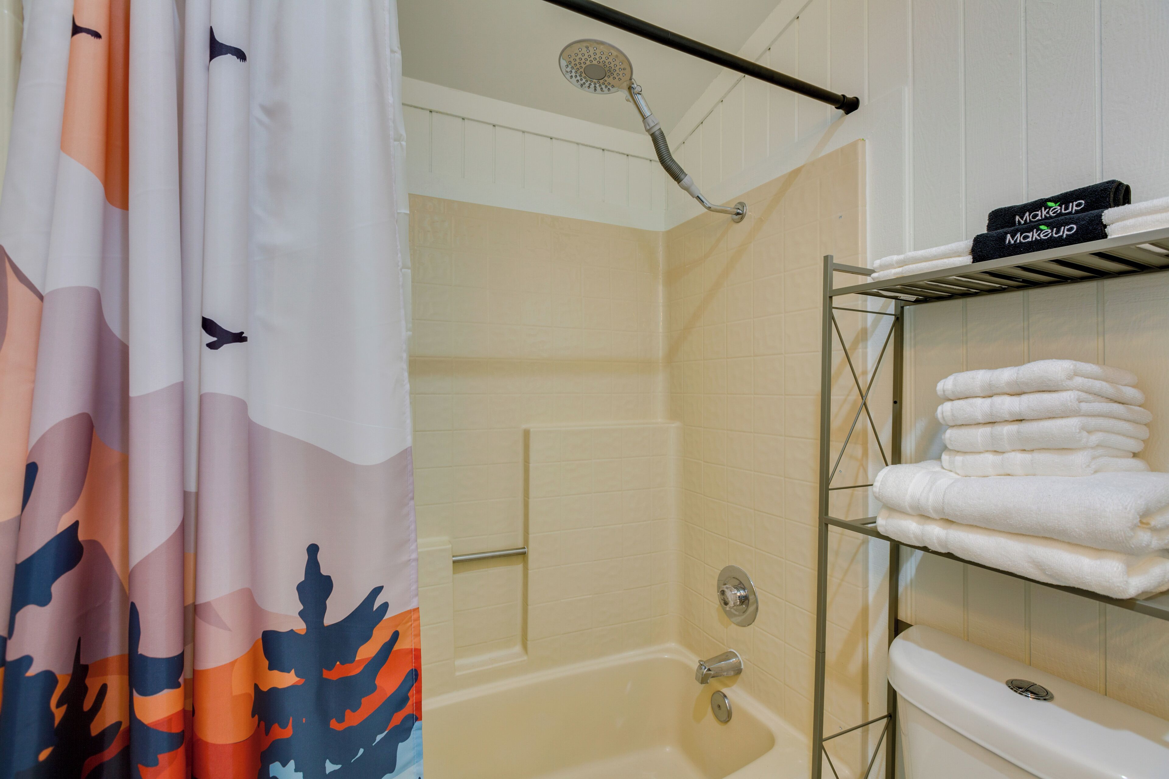 A bathroom with a shower, a toilet, and a shelf with towels.
