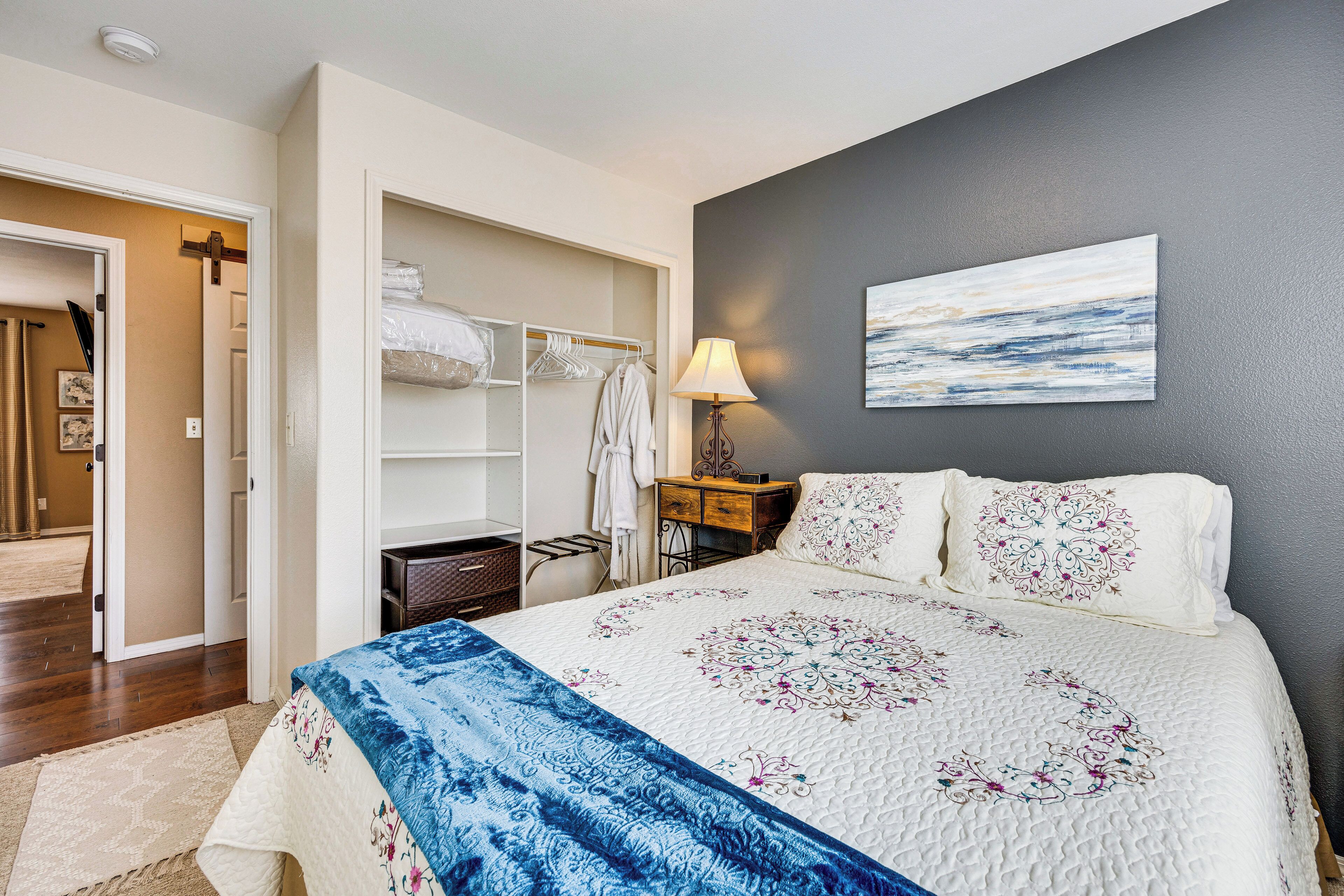 Une chambre d’hôtel avec un lit, une armoire, une table de chevet avec une lampe et un tableau au mur.