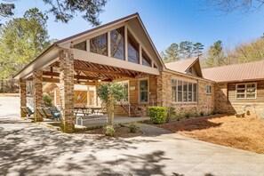 A two-story log cabin with a covered porch, large windows, and a brick exterior. - Lakefront Leesburg Home w/ Private Dock & Ramp! (Leesburg)