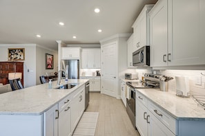 A modern kitchen with white cabinetry, a central island, stainless steel appliances, and a microwave. - Pet-friendly Naples Home w/ Resort-style Pool (Naples)