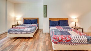 A room with two single beds, each with a wooden headboard and a bedside table with a lamp. The room has white brick walls and a wooden floor. - ATV Trail Access: Mountain-view Briceville Studio! (Briceville)
