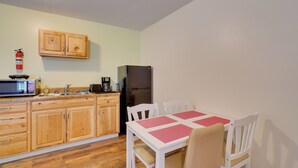 A compact kitchen with wooden cabinets, a microwave, a refrigerator, and a dining table with chairs. - ATV Trail Access: Mountain-view Briceville Studio! (Briceville)