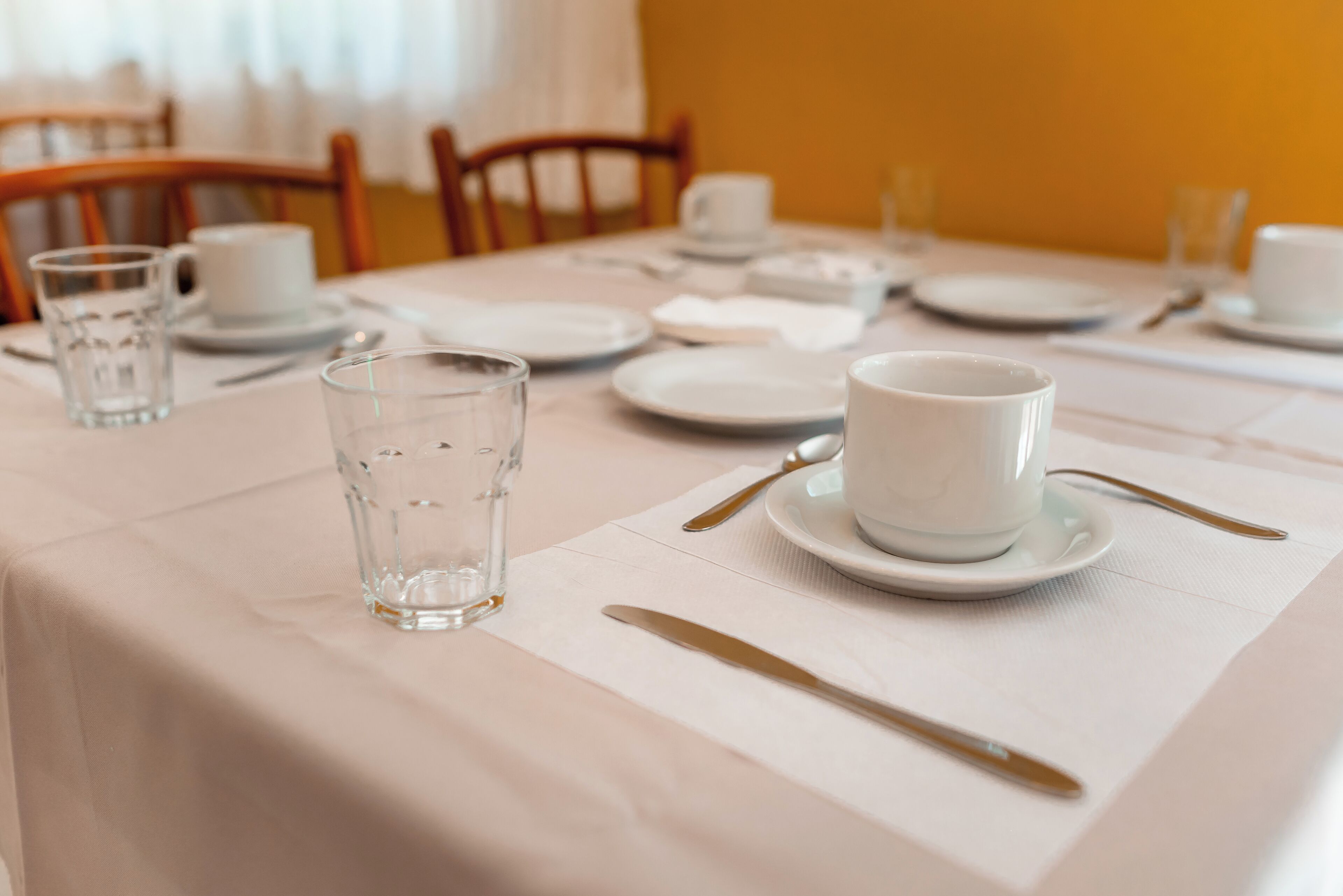 Una mesa de comedor bien puesta con platos, vasos y cubiertos.