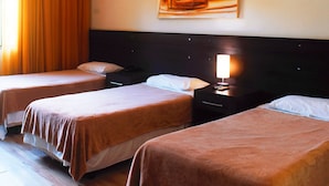 Una habitación de hotel con dos camas individuales, una mesita de noche con lámpara y un cuadro en la pared.