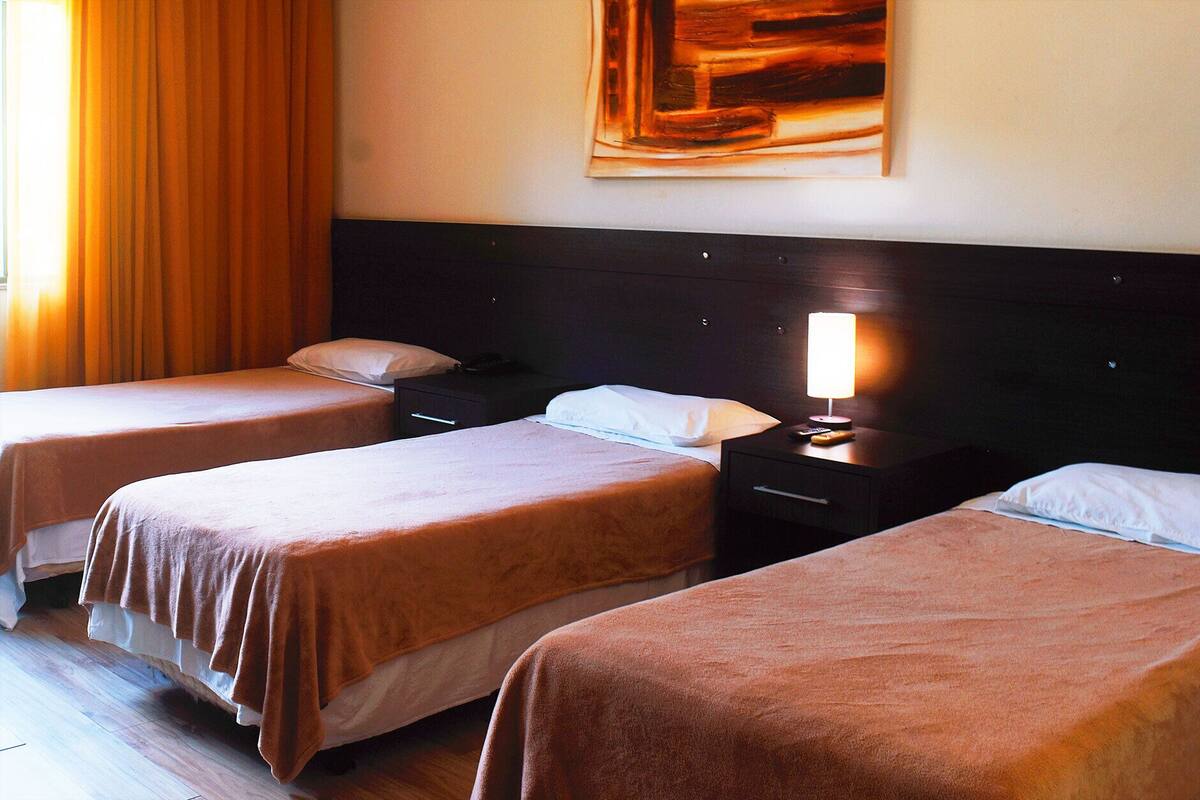Ein Hotelzimmer mit zwei Einzelbetten, einem Nachttisch mit Lampe und einem Bild an der Wand.