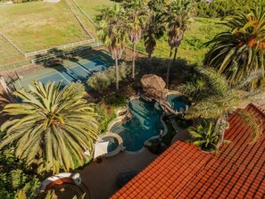 A residential area with a swimming pool surrounded by palm trees and a tennis court. - Villa Serena | Pool, Pickleball & Luxury Retreat (Fallbrook)
