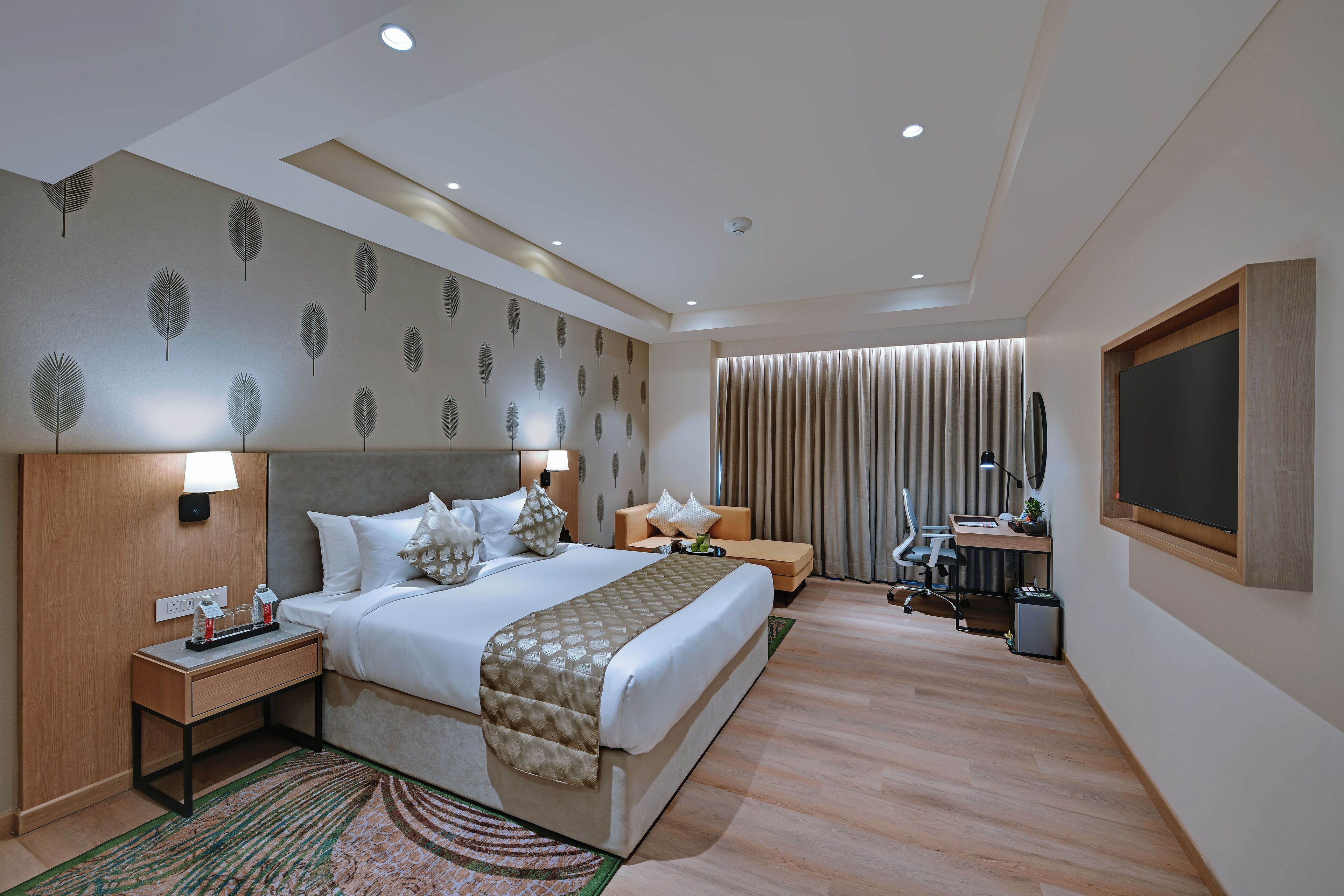 Une chambre d’hôtel moderne dotée d’un grand lit, de tables de chevet, d’un bureau et d’un coin salon.