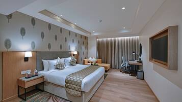Une chambre d’hôtel moderne dotée d’un grand lit, de tables de chevet, d’un bureau et d’un coin salon.