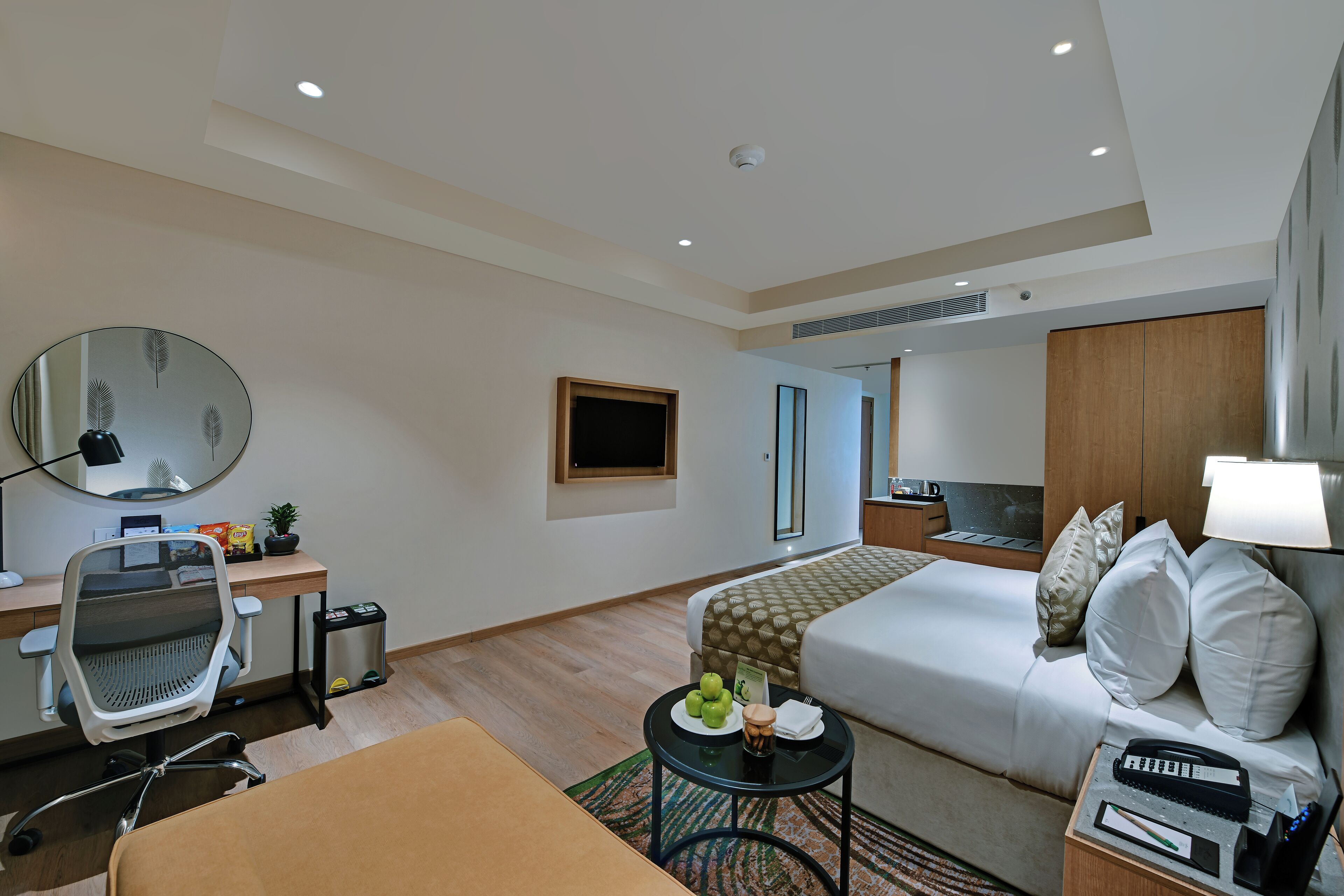 Een hotelkamer met een bed, bureau, stoel en een kleine tafel met een lamp.