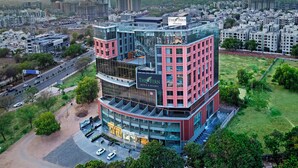 A multi-story hotel with a modern glass facade, multiple balconies, and a prominent sign for The Fern Hotels & Resorts.