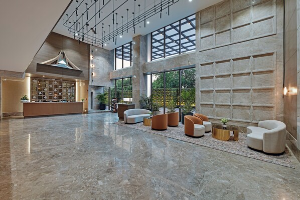 A spacious lobby with a high ceiling, large windows, and a reception desk. - The Fern Residency Gandhinagar, Series by Marriott (Gandhinagar)