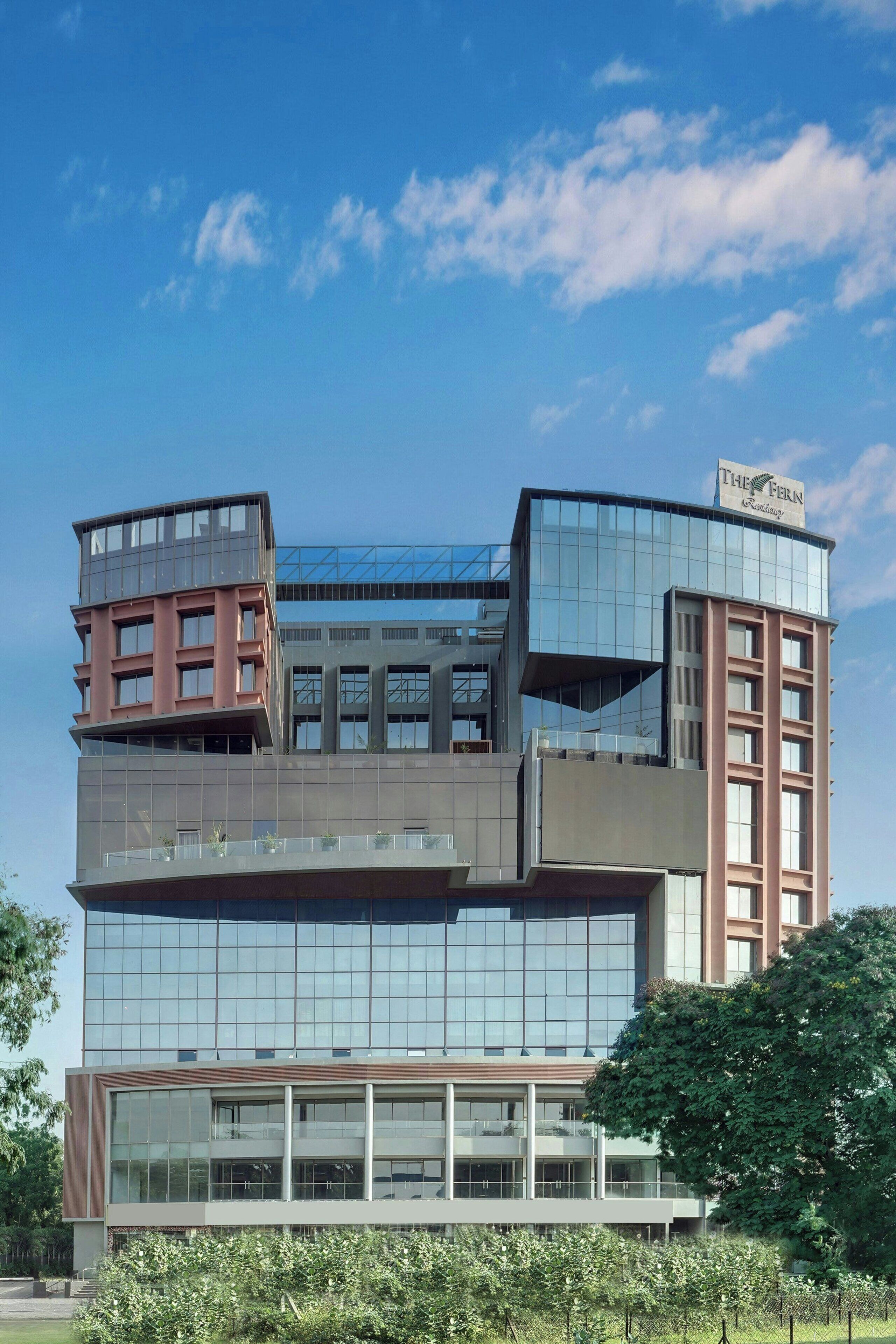 A modern hotel with a unique architectural design, featuring a mix of glass and brick facades, and a prominent sign at the top.