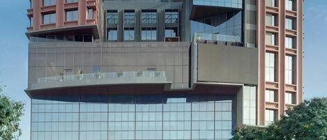 A modern hotel with a unique architectural design, featuring a mix of glass and brick facades, and a prominent sign at the top.