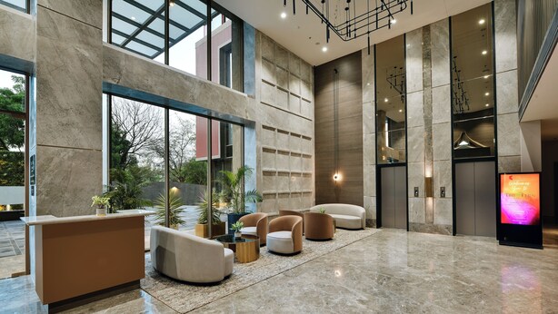 A spacious lobby with a reception desk, seating area, and large windows offering views of the outdoors.