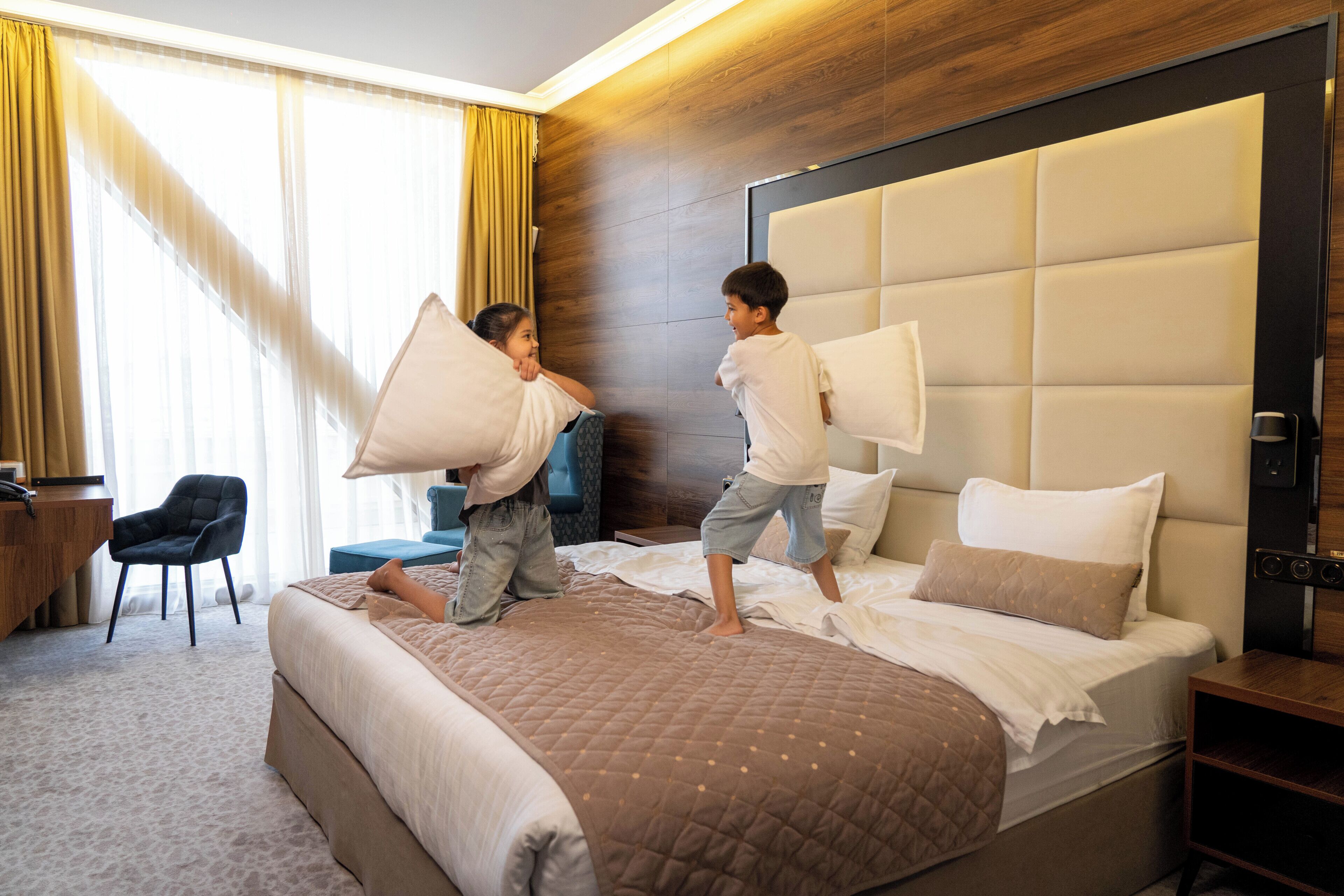 Una camera d'hotel con un letto grande, una testiera in legno, una scrivania e una sedia.