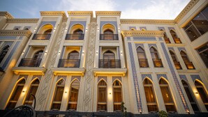 A multi-story building with arched windows and balconies, featuring intricate architectural details and warm lighting.