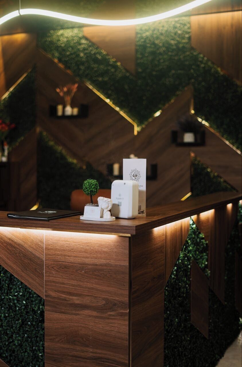 Un mostrador de recepción con detalles de madera, una planta pequeña en maceta y una estación de carga blanca.
