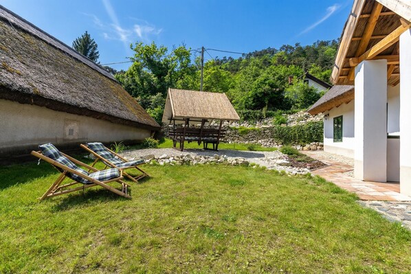 Un espace extérieur rustique doté d’une structure à toit de chaume, d’un espace salon couvert et d’un chemin en pierre.