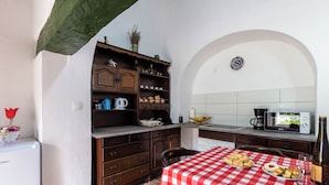 Une cuisine avec une nappe à carreaux rouges et blancs, un four à micro-ondes et une bouteille de vin.