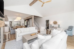 A spacious living area with a large white sofa, a coffee table, and a dining area with a wooden table and chairs.