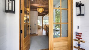 A wooden door with glass panels, a rug on the floor, and a wall-mounted sign with flags.