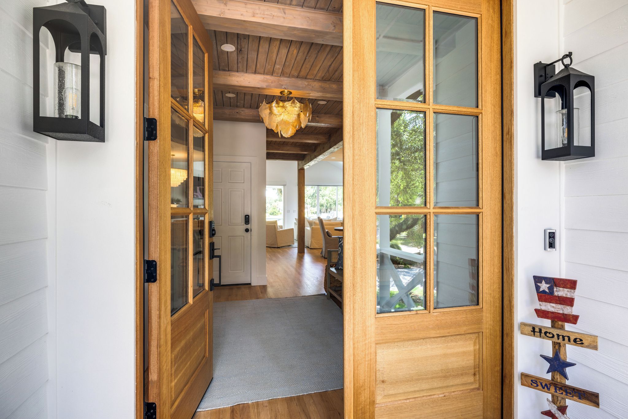 A wooden door with glass panels leading to a room with a ceiling fan and a view of the outdoors.