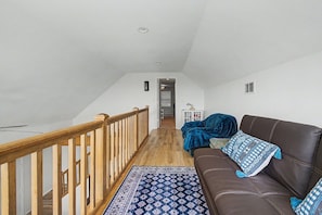 Un loft espacioso con escalera de madera, un sofá de cuero marrón y un tapete estampado.