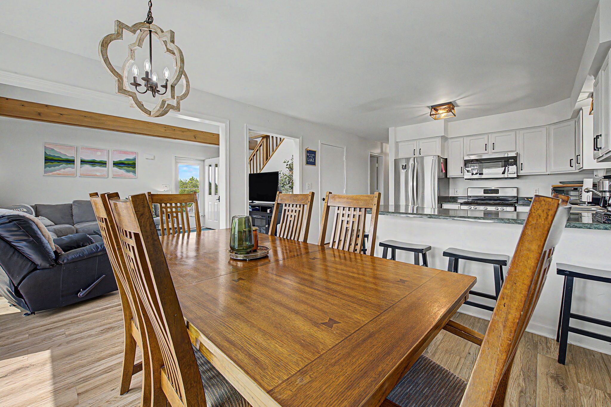 A modern kitchen with white cabinets, stainless steel appliances, and a dining area with a wooden table and chairs.