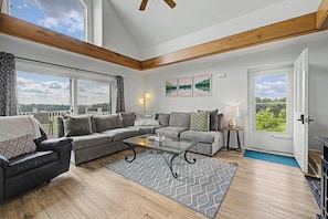 A spacious living room with a large window, a sofa set, a coffee table, and a door leading outside. - Home with LAKE VIEW! Foosball, Skee ball (Apple River)