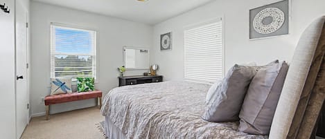 A bedroom with a bed, a bench, a dresser, and a window with blinds.
