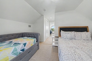 A bedroom with a grey sofa bed and a wooden bed with patterned bedding. - Home with LAKE VIEW! Foosball, Skee ball (Apple River)