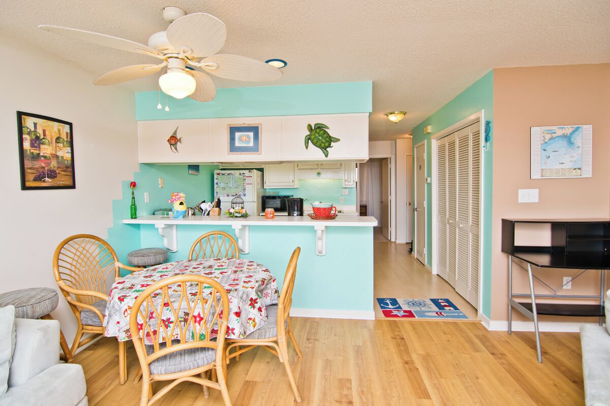 A compact living space with a dining area, kitchenette, and a ceiling fan.