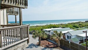 A beachfront property with a wooden deck overlooking the ocean, a parking area, and several mobile homes.