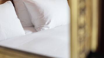 A bed with white linens and pillows, a wooden headboard, and a decorative frame.