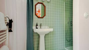 A bathroom with a sink, mirror, and shower.